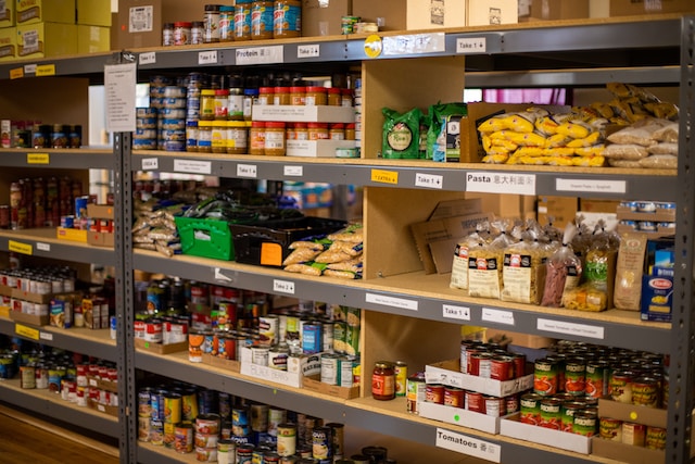 Image of shelves at a food bank labelled with the different types of food (eg pasta, tomatoes). To illustrate blog about food banks.  