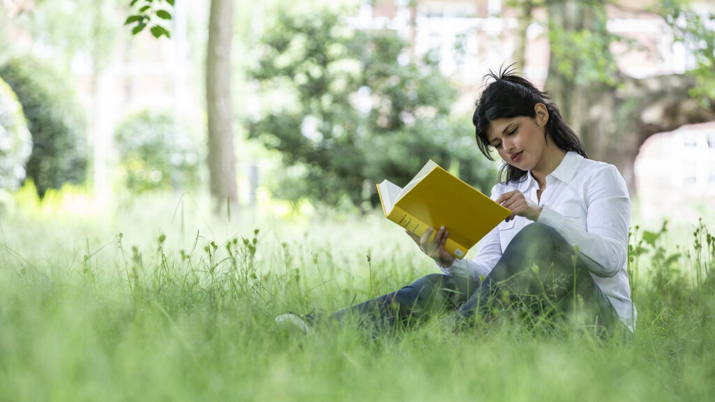 girl reading a book in a field