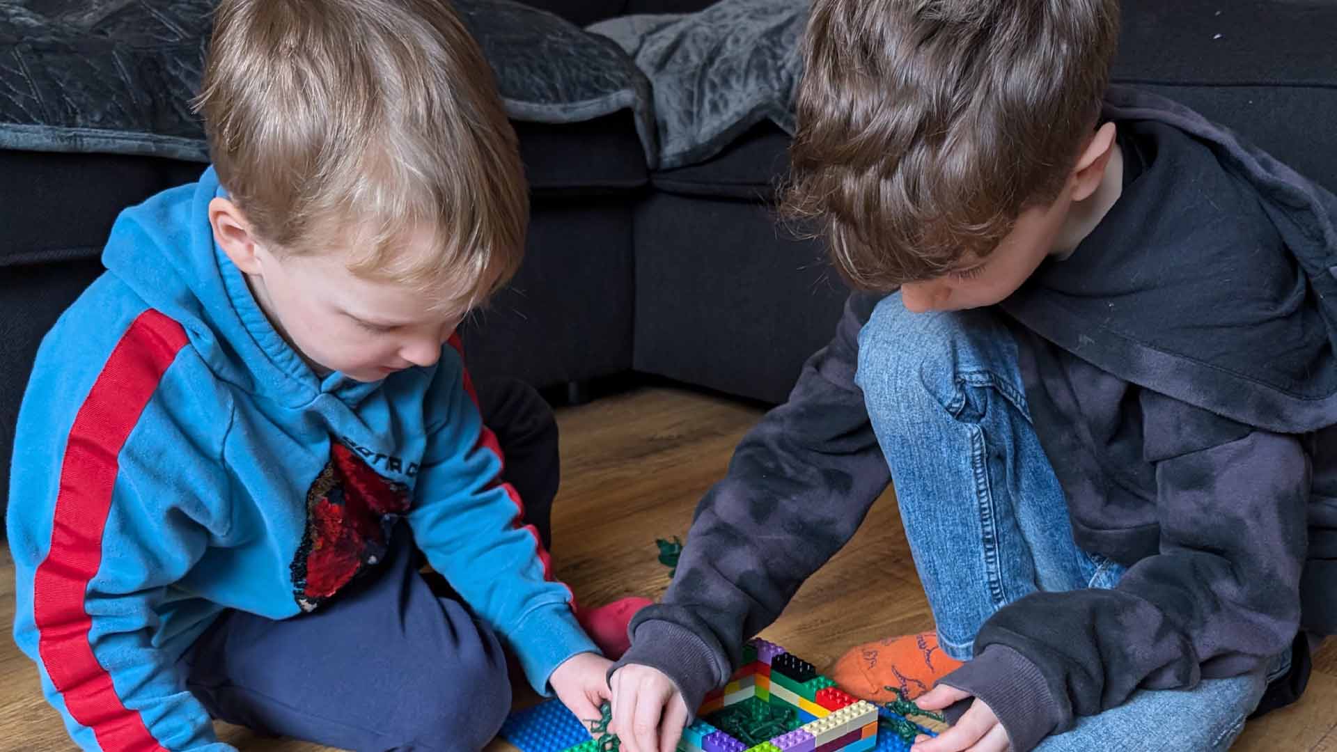 Children playing on a floor with lego
