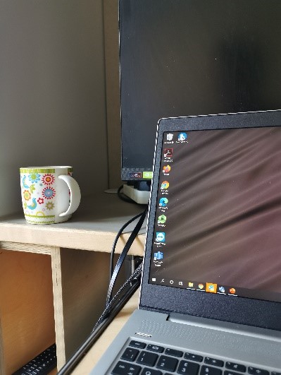 A cup of tea on a desk next to a laptop.