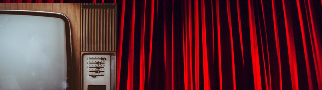 Old (1970's) CRT television in front of a red curtain backdrop.