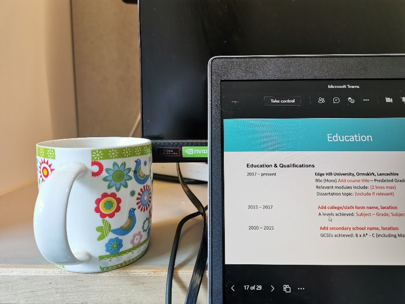 A cup of tea on a desk next to a laptop, watching the perfect CV Webinar.