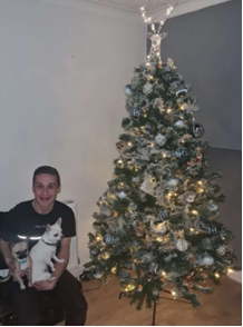 Darren and his cute dog next to a Christmas tree