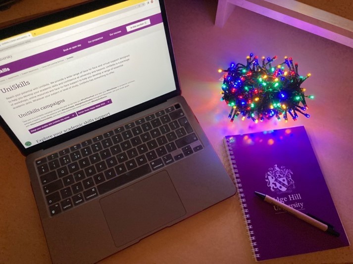 a laptop next to a notebook and ball of fairy lights