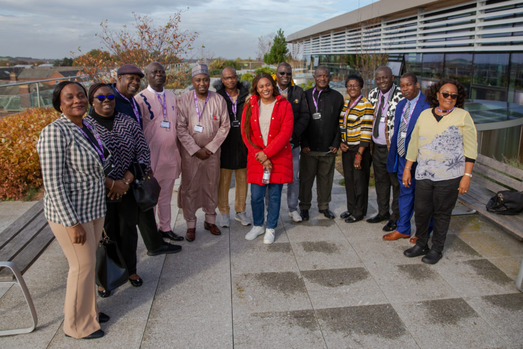 13 individuals are standing, smiling, in a staged photograph taken in the Catalyst rooftop garden.