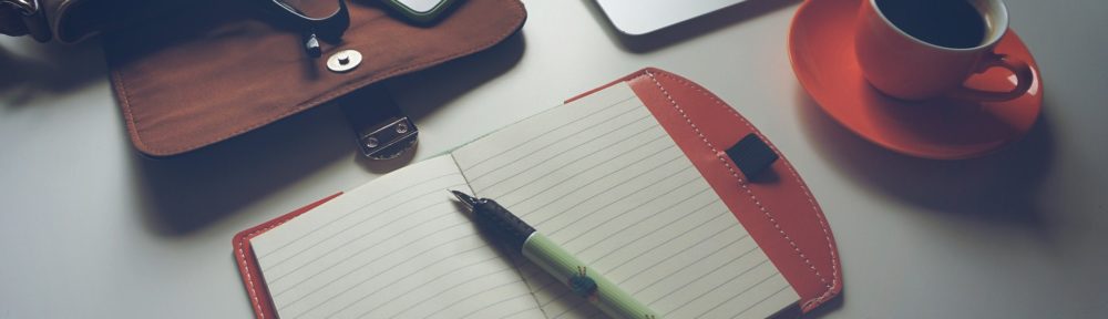 a laptop, notebook and coffee on a desk