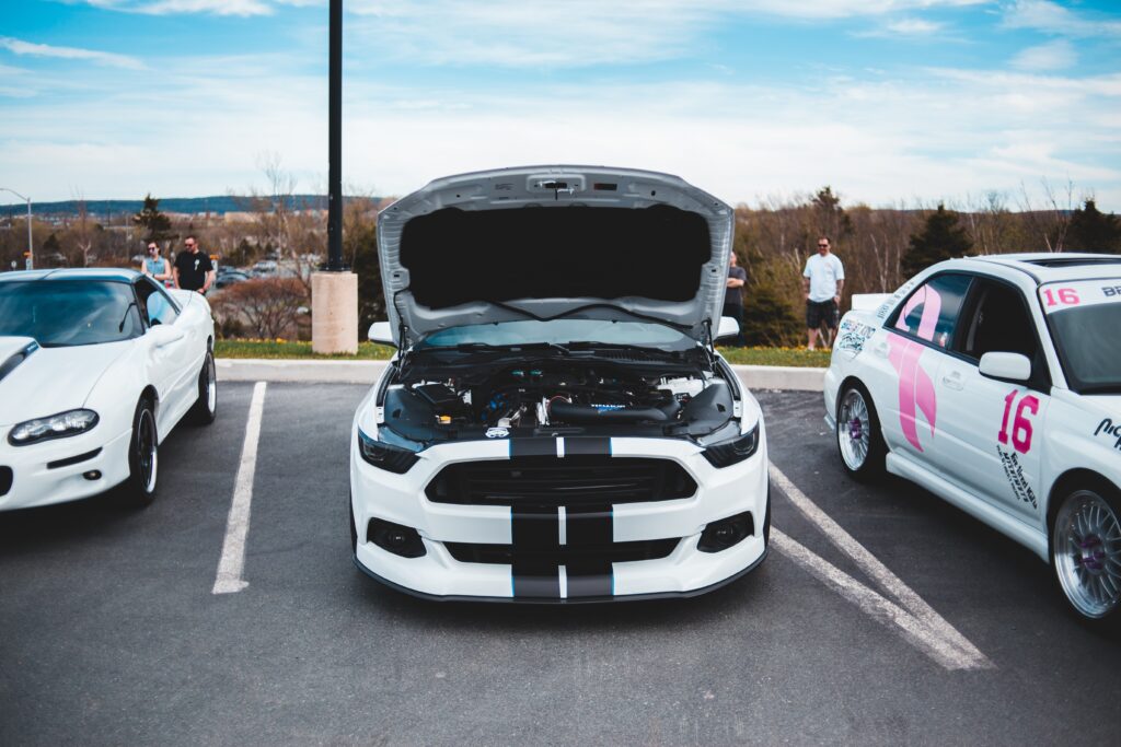 three sports cars in a row. The middle car has its bonnet propped open to reveal the engine.