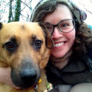 Headshot photograph of Emily Pennington, smiling with her dog Pumpkin.