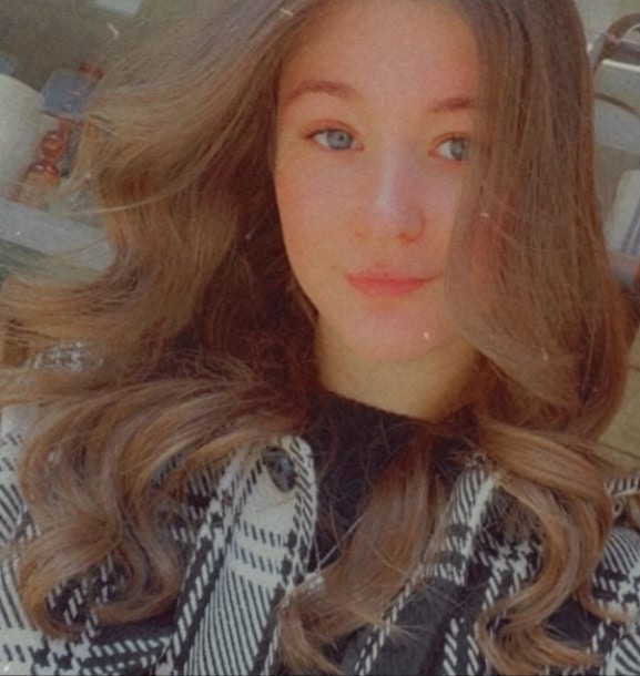 Student Advisor Rosie Sumner. Rosie has long wavy light brown hair. She is wearing a black top with a black and white tartan style jacket.