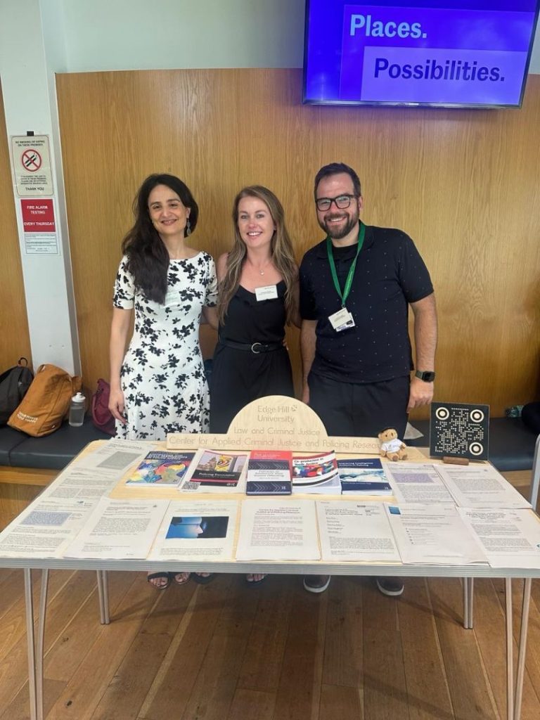 three researchers in front of a table featuring documents at the research showcase and celebration 