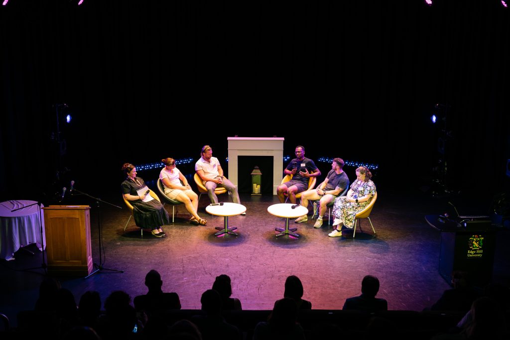A group of 6 people sat around an open circle having a discussion at the Research showcase and celebration