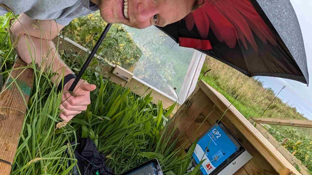 Sven Batke in a rainy field testing greenhouse materials. 